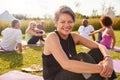 Portrait Of Mature Woman On Outdoor Yoga Retreat With Friends And Campsite In Background