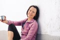 Portrait of mature woman resting after jog near the wall with cup in hand