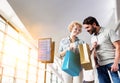 Portrait of mature woman showing present she bought in duty free with her husband at airport