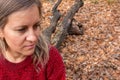 Portrait of mature woman sitting on tree trunk. Thought, meditation or doubt expression. Girl does not look at camera on blurred