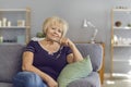 Mature woman smiling and looking at the camera while sitting on a sofa in the living room. Royalty Free Stock Photo