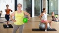 Portrait of mature woman standing with fitness ball during group training at gym Royalty Free Stock Photo