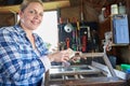 Portrait Of Mature Woman Upcycling Furniture In Workshop At Home