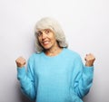 Portrait of a mature woman wearing blue sweater doing a winner gesture Royalty Free Stock Photo