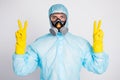 Portrait of medical man worker make v-sign wear white biohazard uniform breathing mask isolated over gray color Royalty Free Stock Photo