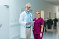 Portrait of medical team, doctor and nurse in uniform, standing in the hospital corridor, looking at the camera and Royalty Free Stock Photo