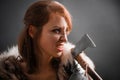 Portrait of a medieval fantasy female warrior in armor armed with an ax, posing in the studio in the dark on a black background