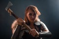 Portrait of a medieval, fantasy viking woman with an ax in her hands in the dark. Royalty Free Stock Photo