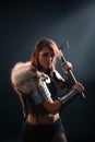 Portrait of a medieval, fantasy viking woman with an ax in her hands in the dark. Royalty Free Stock Photo