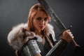 Portrait of a medieval woman warrior in chain mail armor and polar fox fur on her shoulders standing with a sword in hand Royalty Free Stock Photo