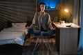 Portrait of a meditating asian girl student sitting on a chair in a room at home at night, a young woman in a lotus Royalty Free Stock Photo