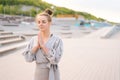 Portrait of meditative Caucasian young woman practicing yoga performing namaste pose with closed eyes outside in city Royalty Free Stock Photo
