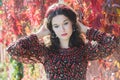 Portrait of melancholy autumn girl with autumn wreath at red floral background of grape woodbine