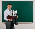 Portrait of a men dressed in business suit with folders, documents and briefcase, posing at blackboard background - learning and