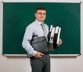 Portrait of a men dressed in business suit with folders, documents and briefcase, posing at blackboard background - learning and