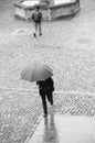 Portrait of men with umbrella on cobbles place with fountain in the city