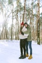 Portrait of men and women in a snowy winter park. Young happy couple are standing and hugging on sunny day in snow-covered park. Royalty Free Stock Photo