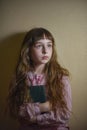 Portrait of a merry little blond girl on a yellow background. A child in a pink shirt. The concept of education