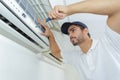 Portrait mid-adult male technician repairing air conditioner Royalty Free Stock Photo