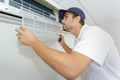 Portrait mid-adult male technician repairing air conditioner Royalty Free Stock Photo