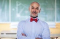 Portrait of mid aged male teacher standing in front of blackboard