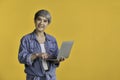 Asian woman 50s holding laptop computer and pointing fingers isolated on colour background Royalty Free Stock Photo