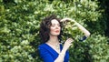 Portrait of a middle-aged brunette in a blue dress next to a blooming linden Royalty Free Stock Photo
