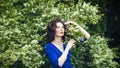 Portrait of a middle-aged brunette in a blue dress next to a blooming linden Royalty Free Stock Photo