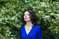 Portrait of a middle-aged brunette in a blue dress next to a blooming linden Royalty Free Stock Photo