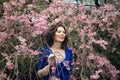 Portrait of a middle-aged brunette in a blue dress next to a cherry blossom Royalty Free Stock Photo