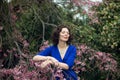 Portrait of a middle-aged brunette in a blue dress next to a cherry blossom Royalty Free Stock Photo