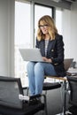 Portrait of middle aged buisnesswoman wearing blazer and eyewear and using laptop at the office Royalty Free Stock Photo