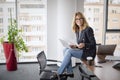 Portrait of middle aged buisnesswoman wearing blazer and eyewear and using laptop while working at the office Royalty Free Stock Photo