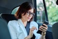 Portrait of middle-aged business woman in car in back passenger seat. Royalty Free Stock Photo