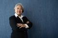 Portrait of middle aged business woman standing isolated on blue background and folded arms looking at the camera with a smile, Royalty Free Stock Photo