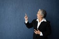 Portrait of middle aged business woman standing isolated on blue background and posing finger pointing and touching, looking at Royalty Free Stock Photo