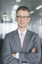 Portrait of middle-aged businessman standing with arms crossed in office Royalty Free Stock Photo