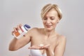 Portrait of middle aged caucasian woman pouring the pills out of the bottle while standing  over grey background Royalty Free Stock Photo