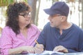 Portrait of middle-aged couple. Man sitting at table in cafe outdoors, discussing having conversation with curly woman. Royalty Free Stock Photo