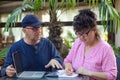 Portrait of middle-aged couple. Man sitting at table in cafe outdoors near laptop, explaining information to woman. Royalty Free Stock Photo
