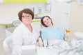 Portrait of middle aged female dentist with smiling patient sitting at dental chair, both looking at camera Royalty Free Stock Photo