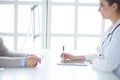 Portrait of middle aged female doctor using digital tablet while sitting at exam room and working Royalty Free Stock Photo