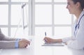 Portrait of middle aged female doctor using digital tablet while sitting at exam room and working Royalty Free Stock Photo