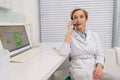 Portrait of middle-aged female medical practitioner sitting at desk with laptop , explain recommendation, discuss Royalty Free Stock Photo