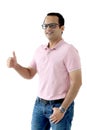 Portrait of a middle aged happy smiling Indian man in a pink T-shirt wearing glasses, standing with giving thumb up isolated on Royalty Free Stock Photo