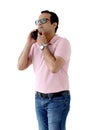 Portrait of a middle aged happy smiling Indian man in a pink T-shirt wearing glasses, standing and talking by mobile phone Royalty Free Stock Photo