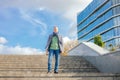 Portrait of middle-aged man businessman wearing jacket, blue scarf, jeans, green T-shirt, going down concrete stairs. Royalty Free Stock Photo