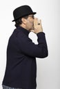 Portrait middle aged man with glasses, bowler hat and round glasses. In profile he whispers with his hands in front of his mouth Royalty Free Stock Photo