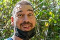 Portrait of middle-aged man with the mask to protect herself from the coronavirus lowered to smile in the forest Royalty Free Stock Photo