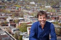 A portrait of a middle-aged man with a short beard smiling on a city background